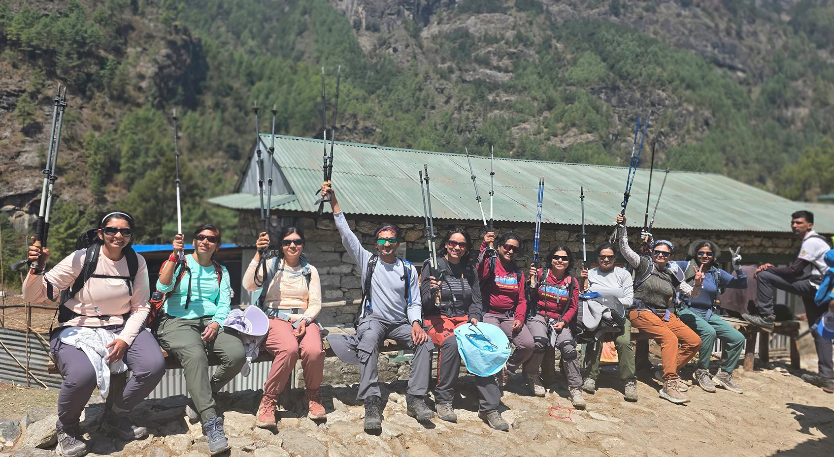 Trekking group raising their poles outside a mountain lodge